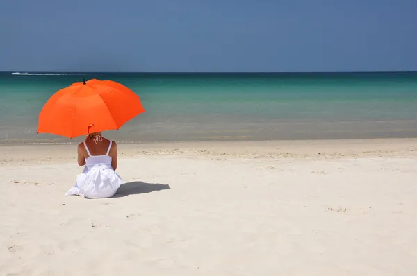 Girl with an orange umbrella on the sandy beach — Stock Photo, Image