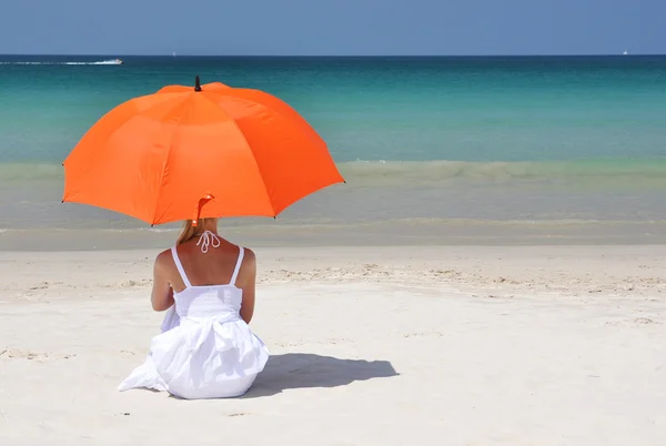Menina com um guarda-chuva laranja na praia — Fotografia de Stock