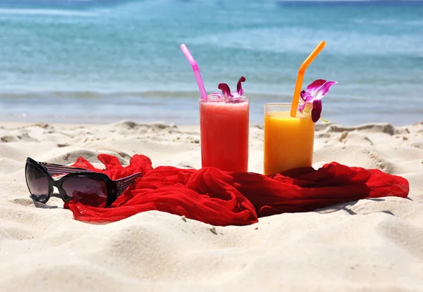 Pair of fruit shakes, red shawl and sunglasses on the tropical b — Stock Photo, Image