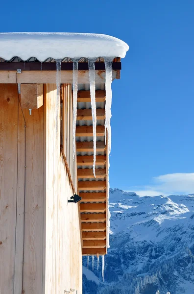 Icicles on the roof against snowy Alps Royalty Free Stock Images