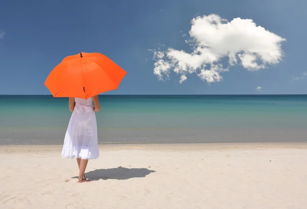 Flicka med ett orange paraply på sandstranden — Stockfoto