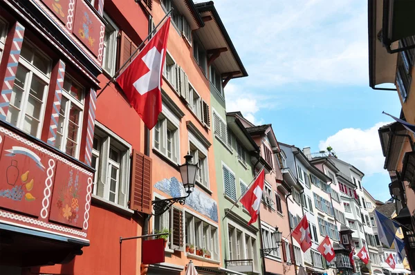 A svájci nemzeti zászlókkal díszített Zürichben régi utca — Stock Fotó