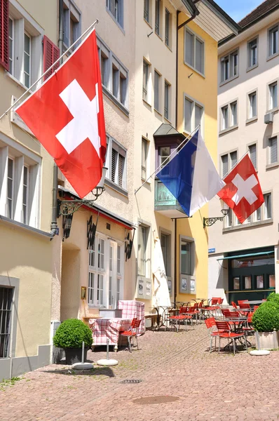 Old street in Zurich decorated with flags for the Swiss Nationa — Stock Photo, Image