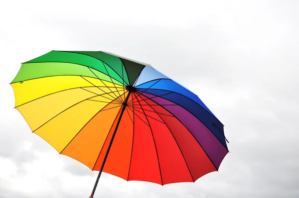 Радужный зонтик против облачного неба — стоковое фото