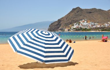 Striped umbrella on the Teresitas beach of Tenerife island. Cana clipart
