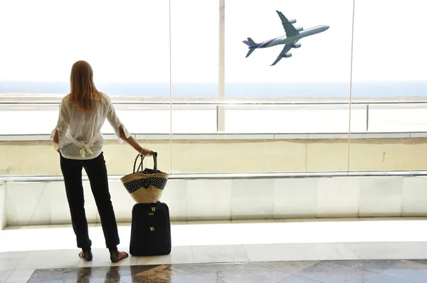 Girl at the airport window looking to the ocean — Stock Photo, Image