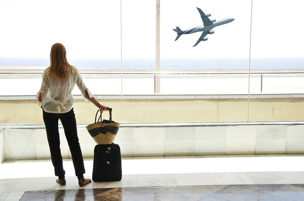 Girl at the airport window looking to the ocean