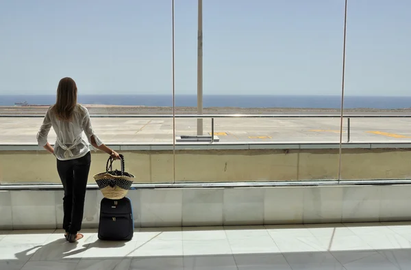 Menina na janela do aeroporto olhando para o oceano — Fotografia de Stock