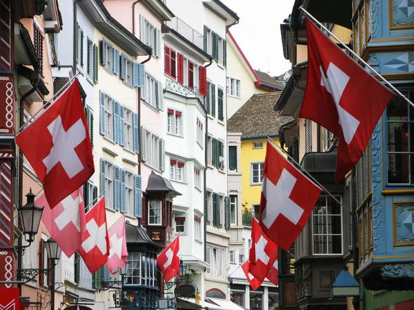 Old street in Zurich decorated with flags for the Swiss Nationa — Stock Photo, Image