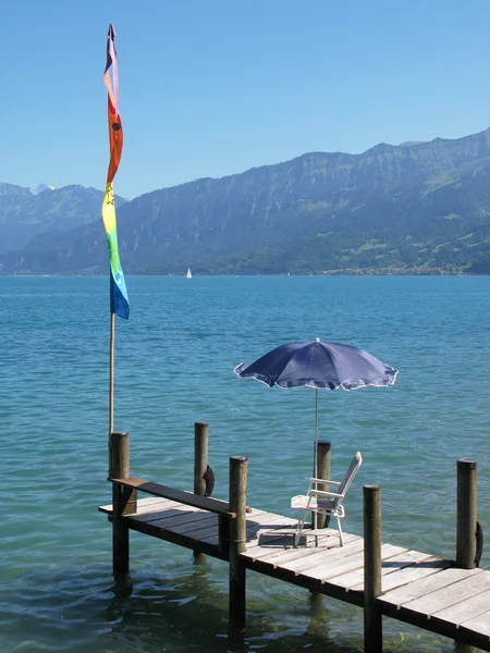 Krzesła i parasol na drewnianym molo nad jeziorem Thun, switzerlan — Zdjęcie stockowe