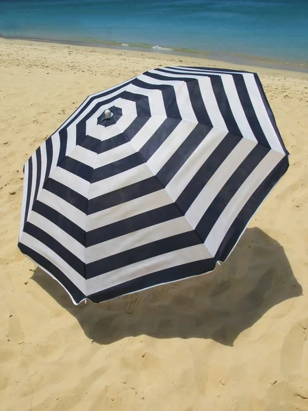 Striped umbrella on a sandy beach — Stock Photo, Image