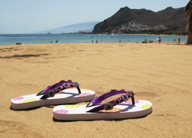 Flip-flops on the sand of Teresitas beach. Tenerife island, Cana clipart