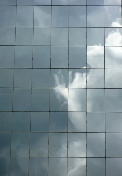 Céu nublado refletido em uma parede de vidro de um edifício alto — Fotografia de Stock