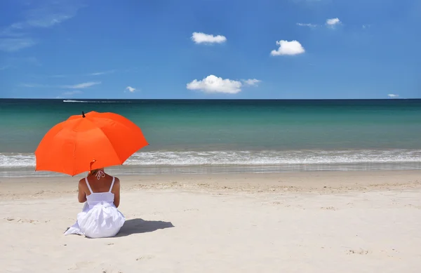 Chica con un paraguas naranja en la playa de arena —  Fotos de Stock