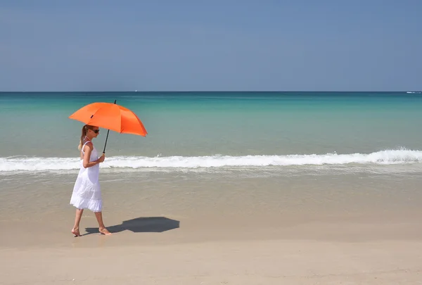 Chica con un paraguas naranja en la playa de arena —  Fotos de Stock