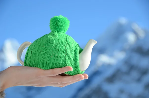 Tekanna i knuten hatten i handen mot alpina landskap — Stockfoto