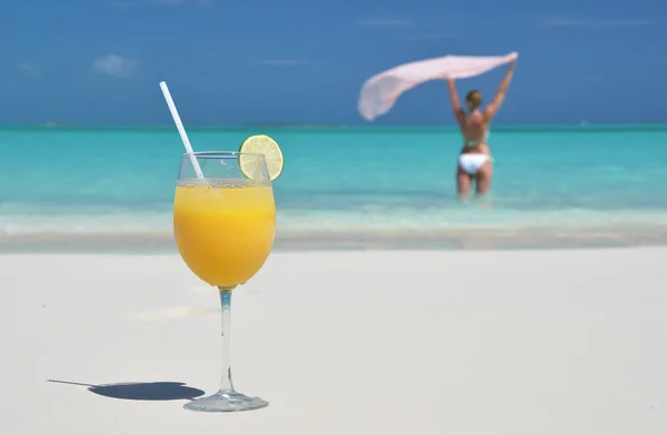 Un vaso de jugo de naranja en la playa de arena de Exuma, Bahamas — Foto de Stock
