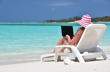 tropik sahilde bir dizüstü bilgisayar ile bir kız. Exuma, bahamas