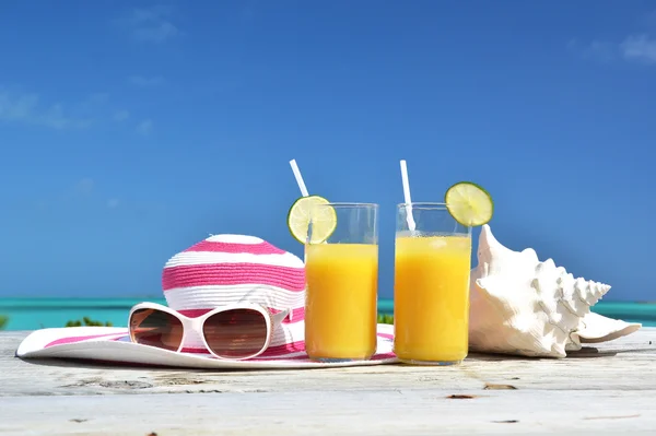 Sumo de laranja, chapéu, óculos de sol e concha na praia tropical. Exuma, Bahamas — Fotografia de Stock