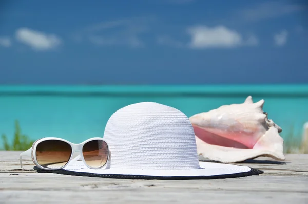 Óculos de sol, chapéu e concha contra o oceano. Exuma, Bahamas — Fotografia de Stock