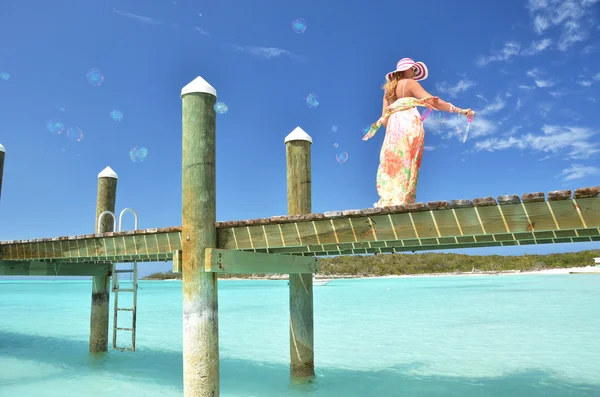 Mädchen auf dem Holzsteg, die Seifenblasen machen. exuma, bahamas — Stockfoto