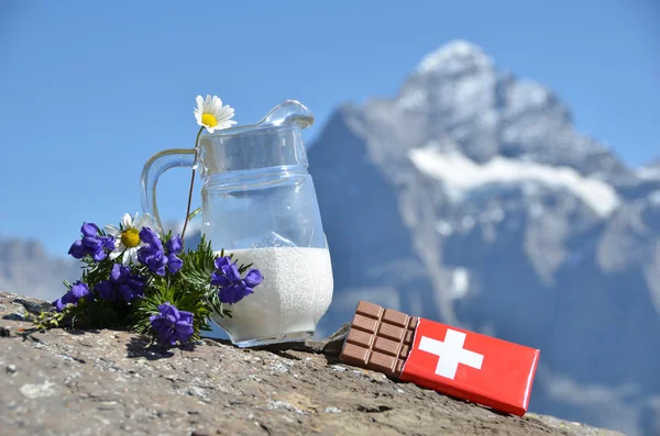 Swiss chocolate and jug of milk against mountain peak. Switzerla — Stock Photo, Image