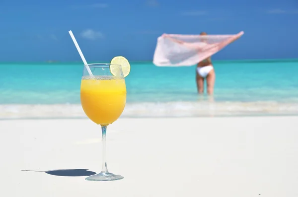 Un vaso de jugo de naranja en la playa de arena de Exuma, Bahamas — Foto de Stock