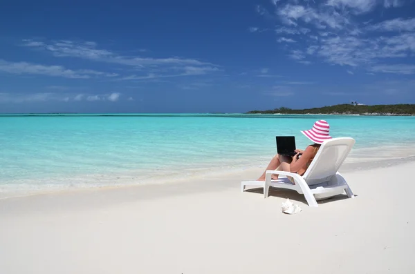 tropik sahilde bir dizüstü bilgisayar ile bir kız. Exuma, bahamas