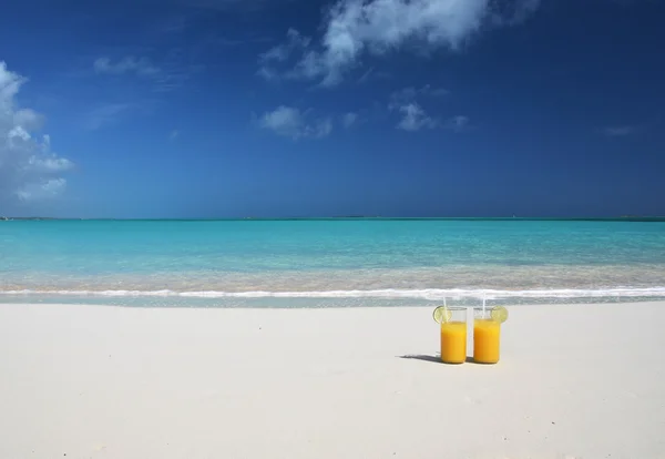 Δύο ποτήρια χυμό πορτοκαλιού στην αμμώδη παραλία — Φωτογραφία Αρχείου