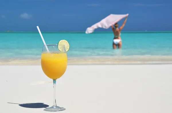 Un vaso de jugo de naranja en la playa de arena de Exuma, Bahamas — Foto de Stock