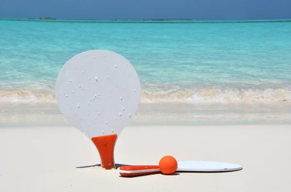 Two rackets and a ball on the sandy beach — Stock Photo, Image