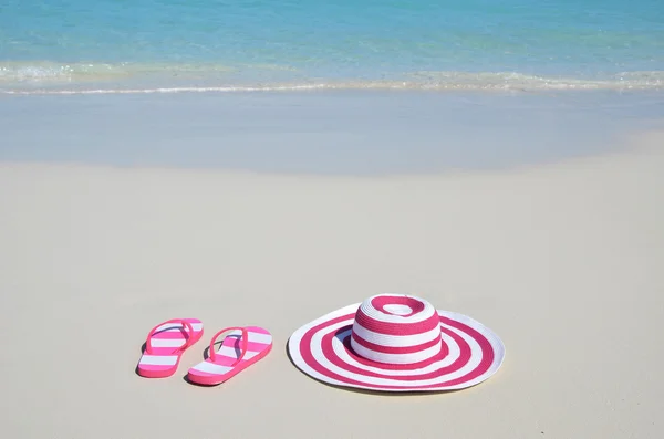 Slippers en hoed op het strand — Stockfoto