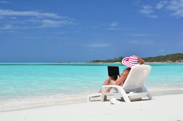 一台笔记本电脑在热带海滩上的女孩。埃克苏马巴哈马 — 图库照片