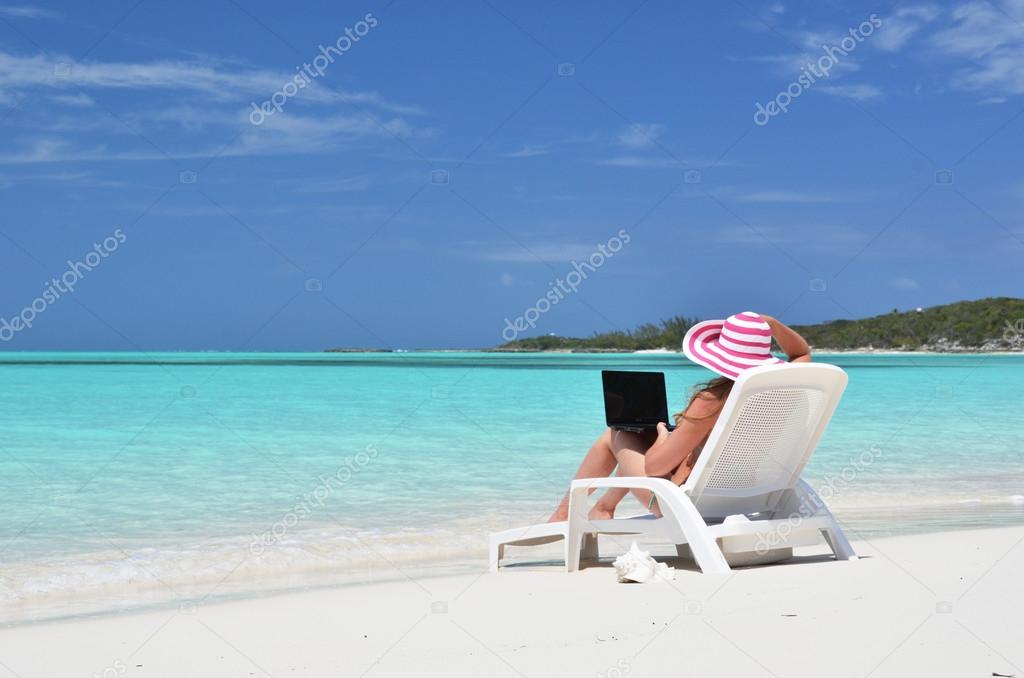 Girl with a laptop on the tropical beach. Exuma, Bahamas