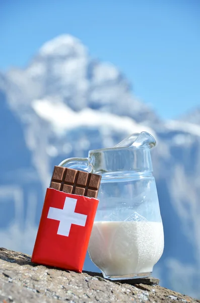 Cioccolato svizzero e brocca di latte contro la vetta della montagna. Svizzera — Foto Stock
