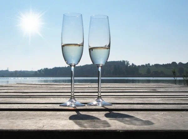 Two champagne glasses against a lake — Stock Photo, Image