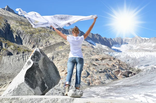 Girl holding a flapping shawl against Rhone glacier. Switzerland — Stock Photo, Image