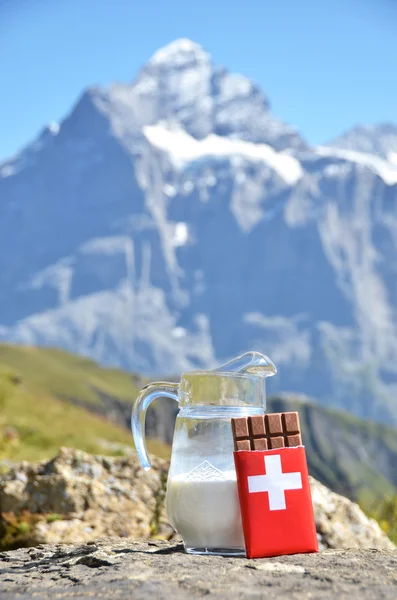 Cioccolato svizzero e brocca di latte contro la vetta della montagna. Svizzera — Foto Stock