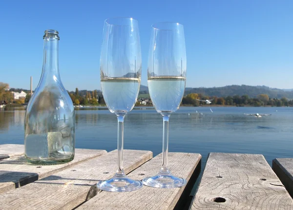 Two champagne glasses against a lake — Stock Photo, Image