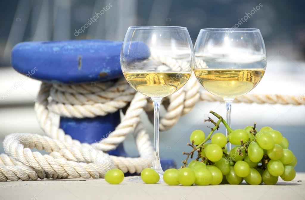 Pair of wineglasses and grapes against the yacht pier of La Spez
