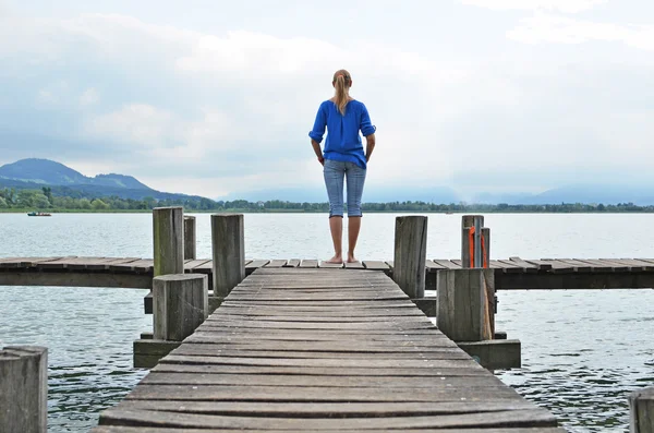 Girl on the wooden jetty. Switzerland — Stock Photo, Image