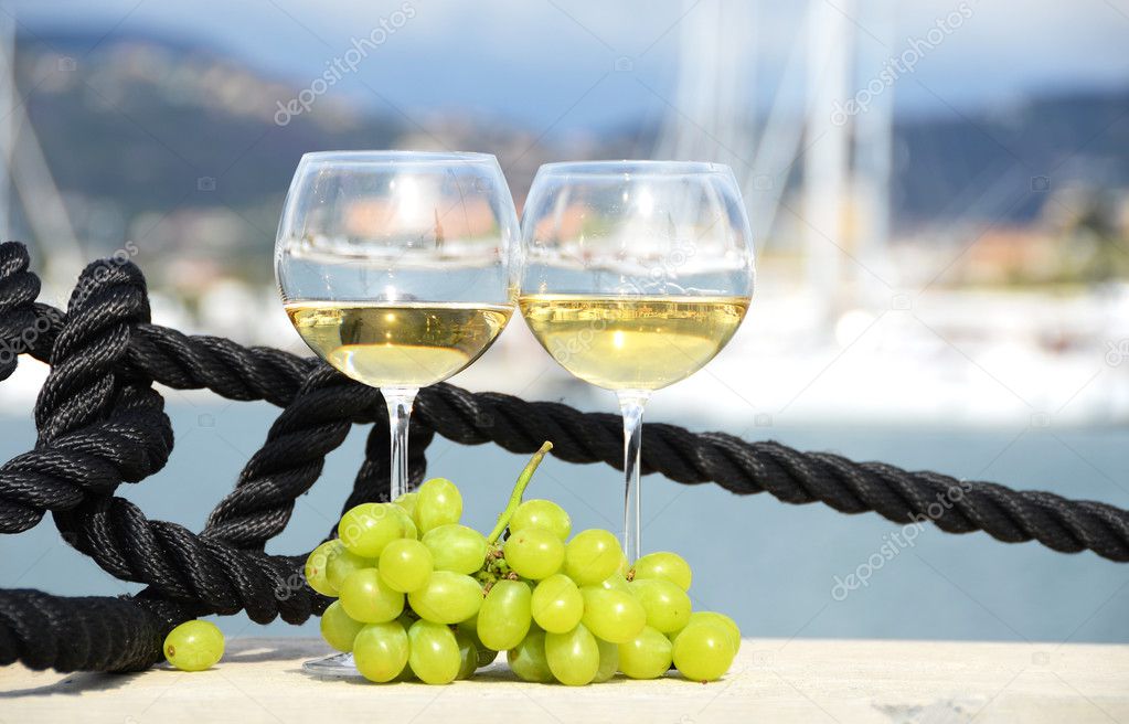 Pair of wineglasses and grapes against the yacht pier of La Spezia, Italy