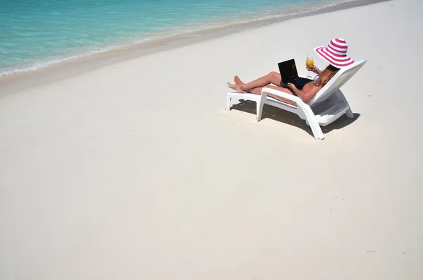 Meisje met een laptop op het tropisch strand. — Stockfoto