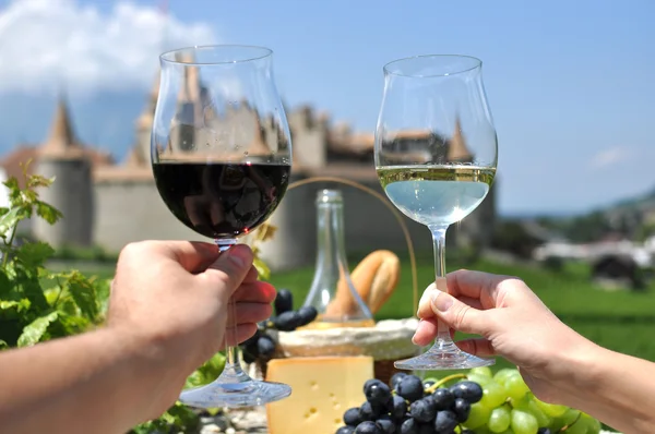 Dos manos sosteniendo las gafas de vino contra Chateau d 'Aigle, Suiza — Foto de Stock