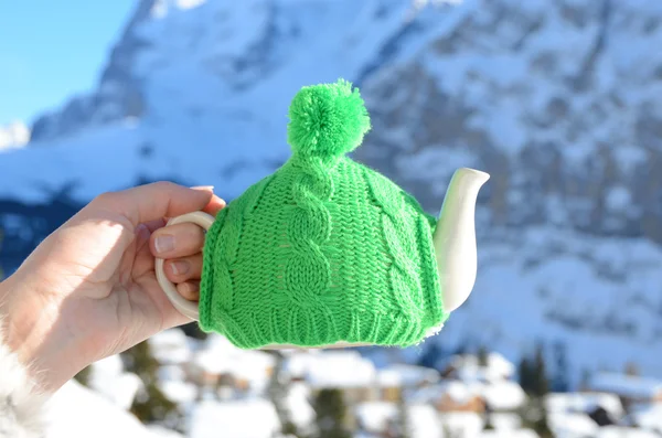 Tea pot in the knotted cap in the hand against mountain scenery — Stock Photo, Image