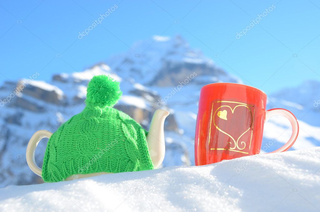 Tea pot in the cap and a cup against alpine scenery