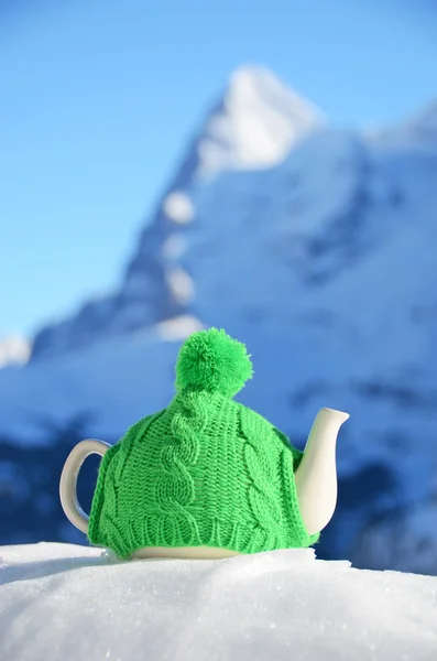 Panela de chá na tampa de malha na neve — Fotografia de Stock