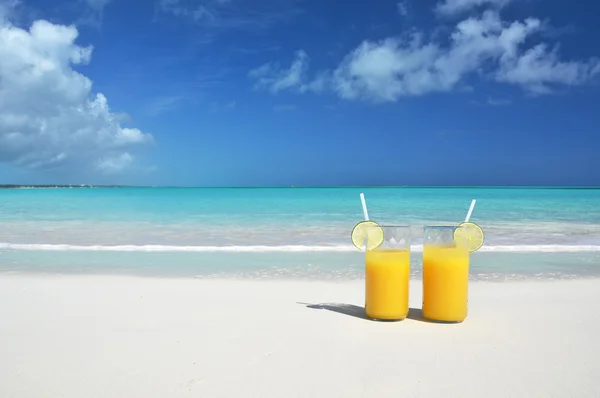 Два стакана апельсинового сока на песчаном пляже — стоковое фото