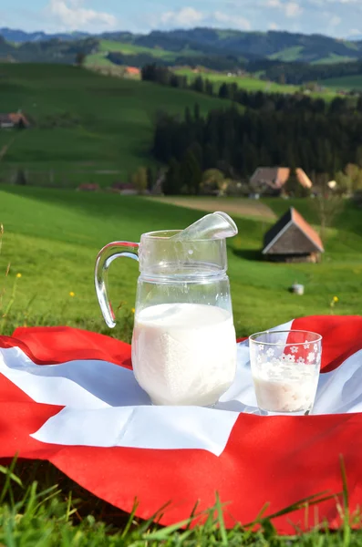 Kruik van melk op de Zwitserse vlag. — Stockfoto