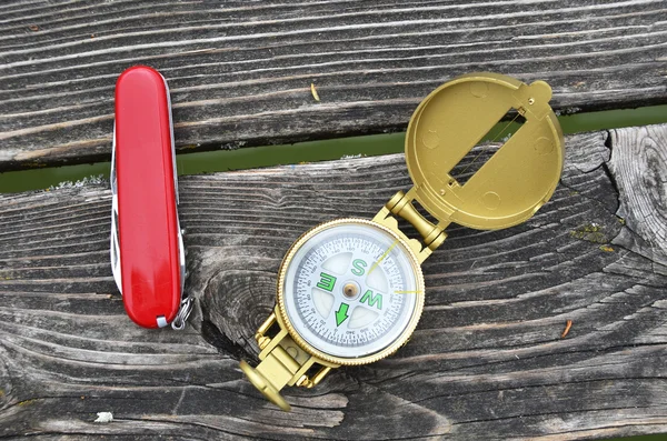 Compass and pocket knife on the wooden background — Stock Photo, Image